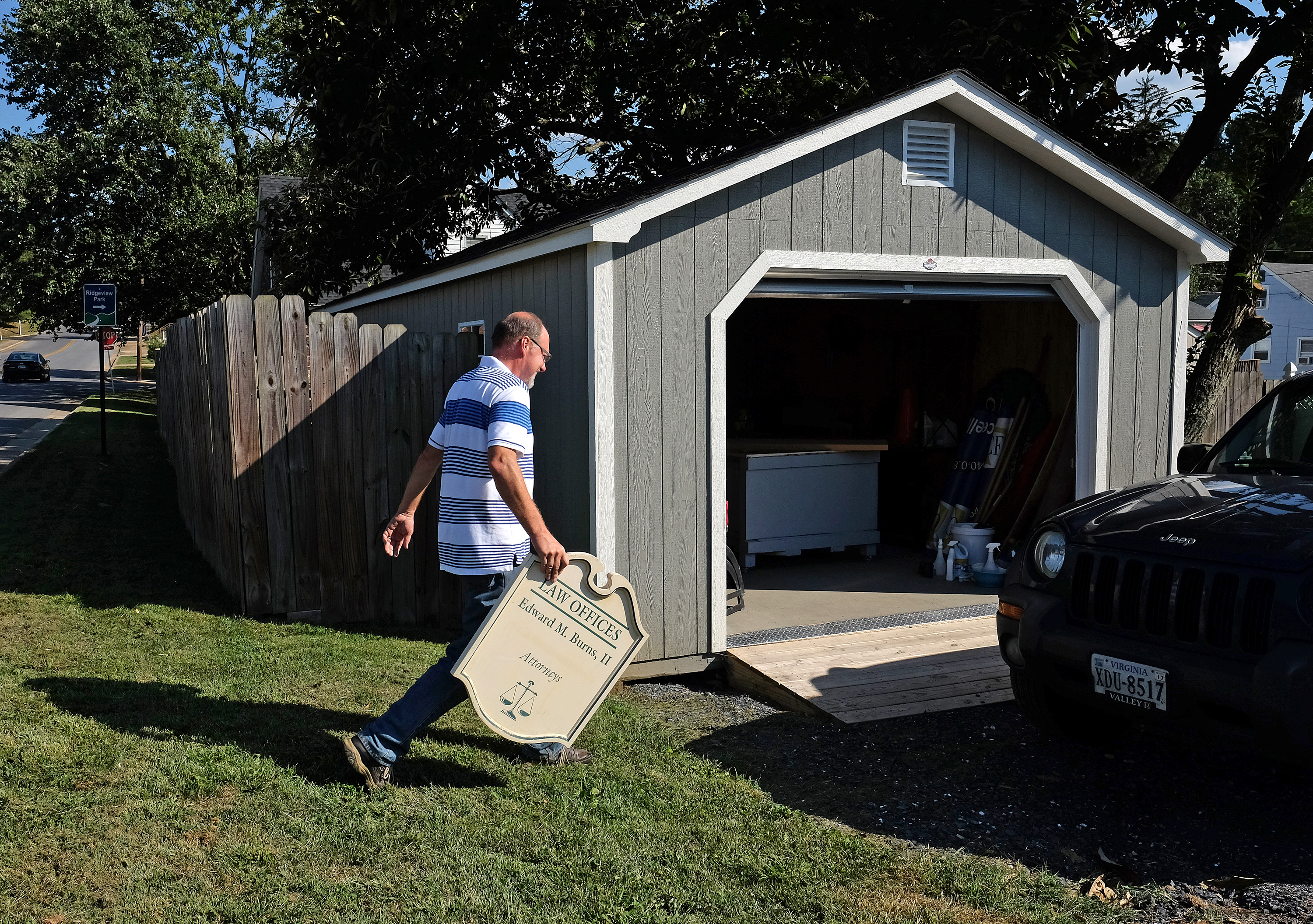 Mark Hackley, President Augusta Sign Company, carries a sign into his shop to repair, Friday, September 9, 2016. (Photo by Norm Shafer).